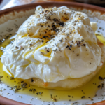 Freshly made burrata cheese on a plate, garnished with basil and a drizzle of olive oil