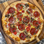 Homemade familial pizza with generous toppings, cheese, and colorful vegetables on a baking sheet, served family-style.