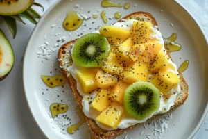 Overhead view of thick tropical yogurt custard toast topped with mango, pineapple, kiwi, and passionfruit on a white plate, drizzled with honey and coconut.