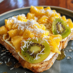 Enormous serving of tropical yogurt custard toast topped with mango, pineapple, kiwi, passionfruit, and coconut, photographed by an amateur on a phone.