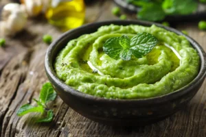 Silky green pea purée swirled in a bowl with fresh mint and olive oil
