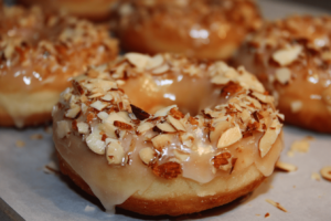 Close-up of almond mochi donut with glossy almond glaze and toasted sliced almonds