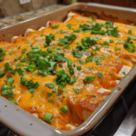 Cheesy Buffalo Chicken Enchiladas baked in a pan with buffalo sauce and green onions