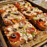 Texas toast pizzas with melted cheese and pepperoni on a baking sheet