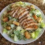 Single serving of Caesar Chicken Salad on a plate with chicken and croutons