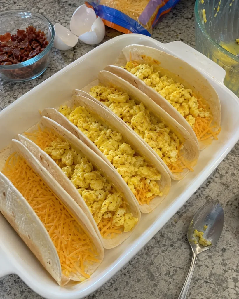 Assembling Baked Breakfast Tacos with cheese and scrambled eggs