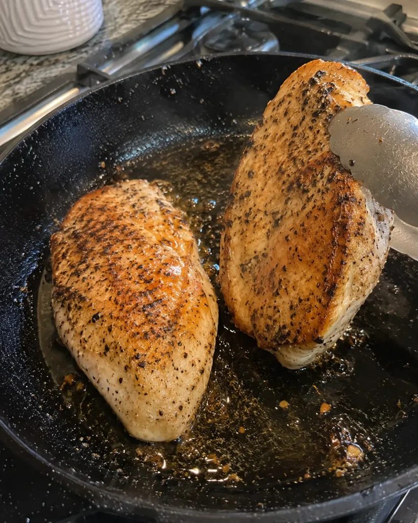  Chicken breasts searing in a skillet for Caesar Chicken Salad