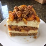 Slice of Peach Cobbler Cheesecake Recipe showing peach and streusel layers Title: Peach Cobbler Cheesecake Slice