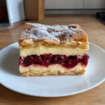 A slice of Cherry Karpatka Recipe showing the layered filling