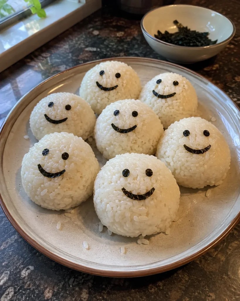 Emoji rice balls with smiley nori faces on a plate