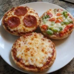 Three English Muffin Pizzas with different toppings on a plate