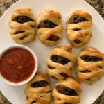 Close-up of Halloween Mummy Meatballs with crescent dough bandages and olive eyes