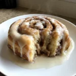 A single Heavy Cream Cinnamon Roll on a plate showing the soft interior