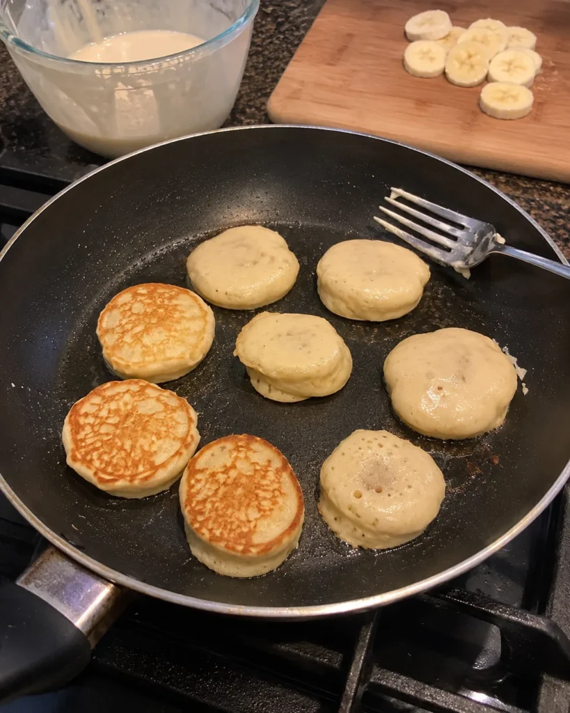 Banana Pancake Bites cooking in a nonstick skillet until golden brown