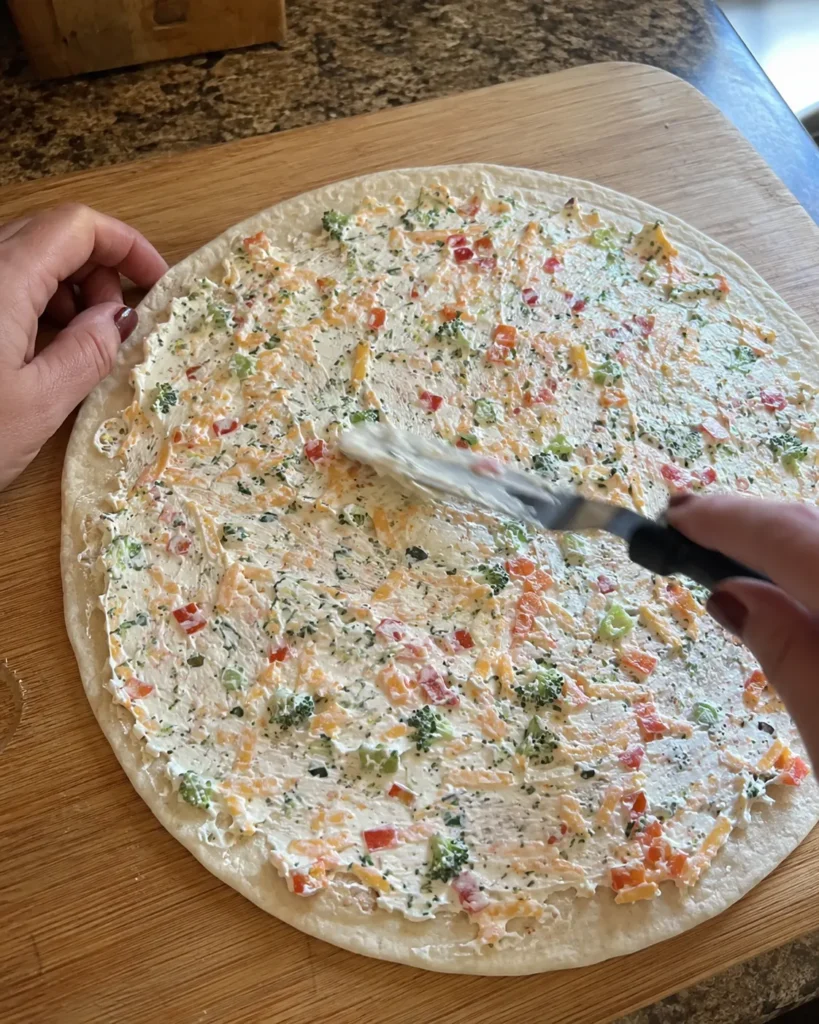 Spreading filling on a tortilla for Cheese & Veggie Roll-Ups