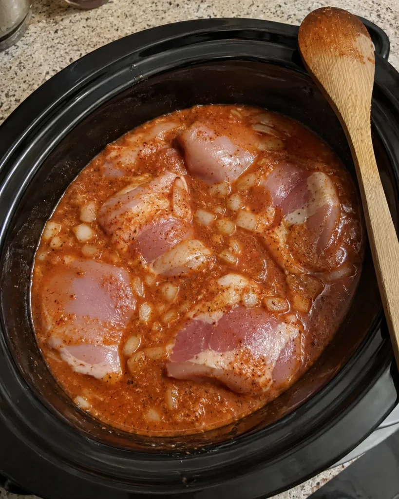 Raw chicken thighs in tomato sauce before cooking Crockpot Butter Chicken