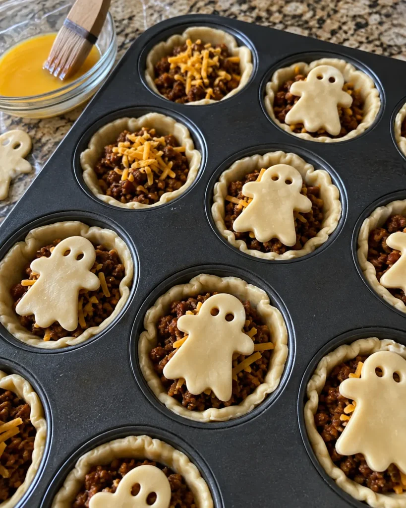 Assembling Ghost Mini Taco Pies in a muffin tin before baking