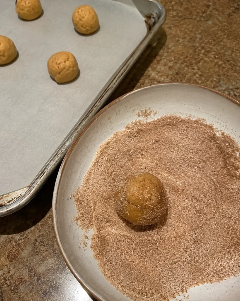 Pumpkin Spice Cookies dough ball being rolled in cinnamon sugar
