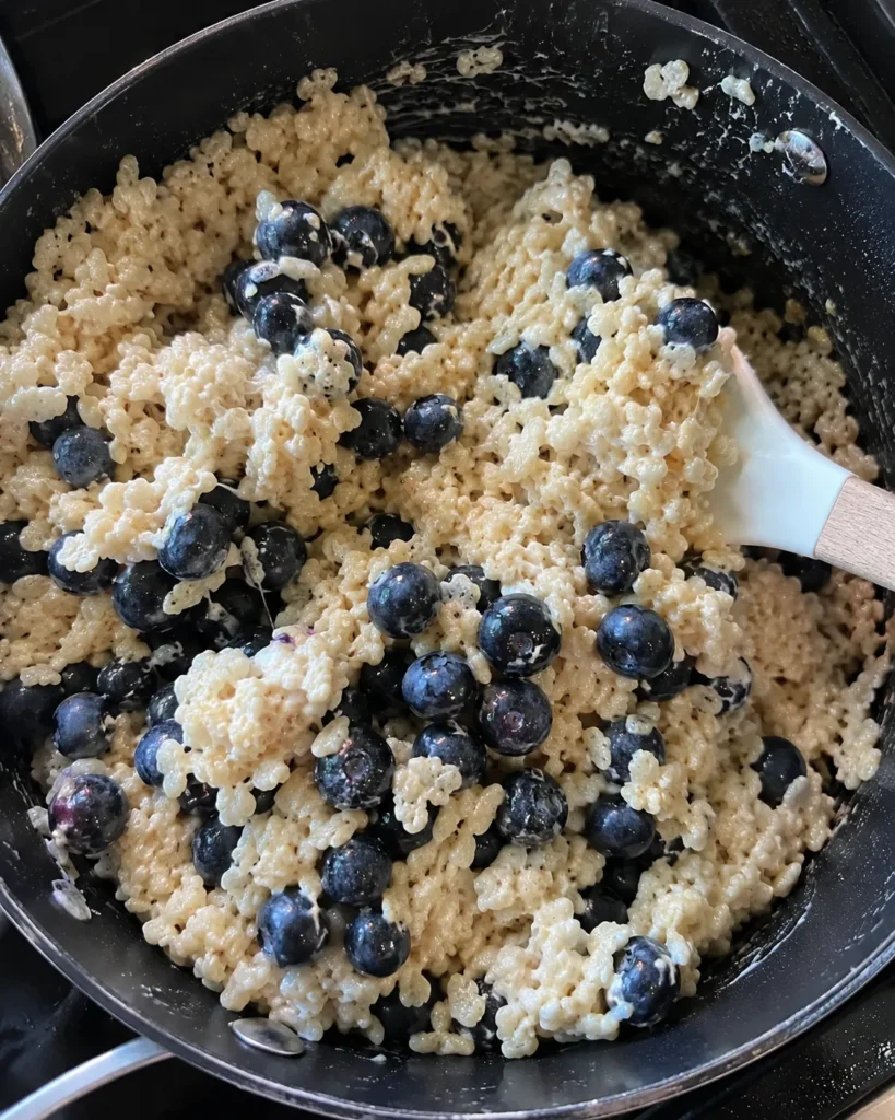 Folding fresh blueberries into Blueberry Rice Krispies Treats mixture