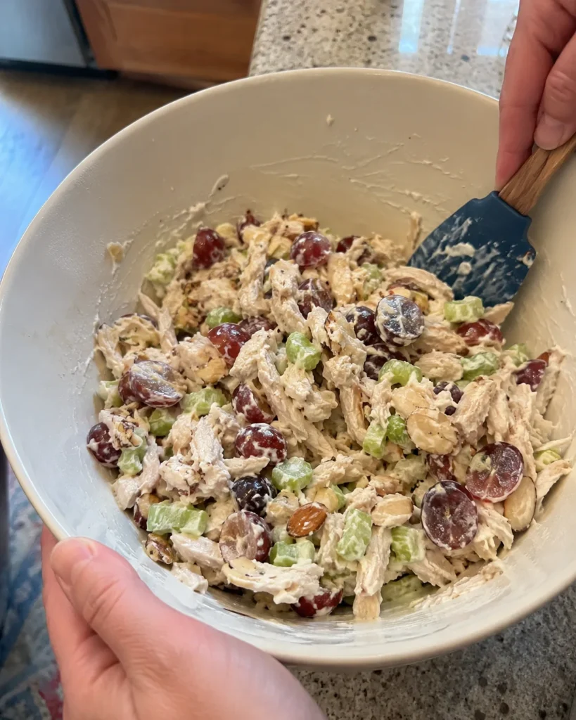 Mixing Chicken Salad with Grapes and Almonds in a bowl