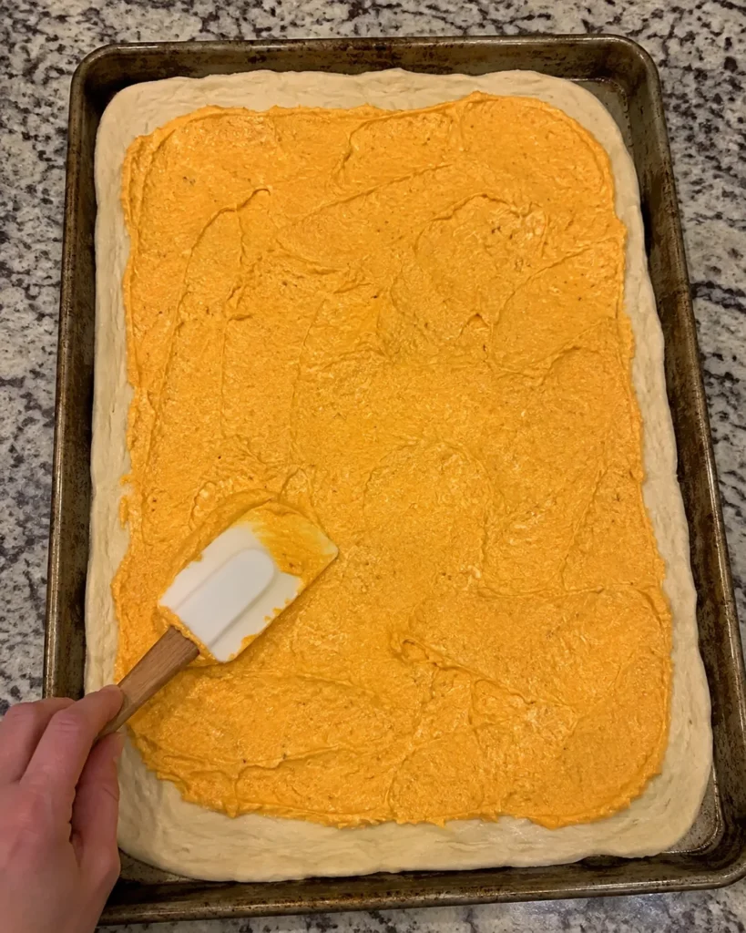 Spreading pumpkin ricotta mixture over flatbread dough