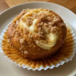 Close-up of a single Pumpkin Cream Cheese Muffin with a visible cream cheese swirl