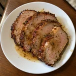 Thick slices of Air Fryer Pork Loin on a white plate with pan juices