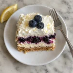 Single slice of blueberry lemon icebox cake on a white plate showing cream and compote layers