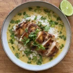 Overhead view of coconut chicken brothy rice in a bowl on a wooden cutting board