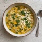 Overhead view of brothy rice with corn, jalapeño, and crumbled Cotija cheese