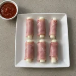 Overhead view of ham and cheese sticks on a white plate with marinara sauce