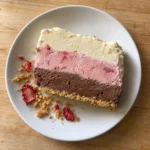 A single slice of no-churn Neapolitan ice cream cake showing three distinct layers and a cookie crust